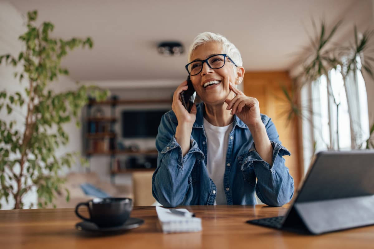 femme senior qui travaille devant une tablette tout en étant au téléphone