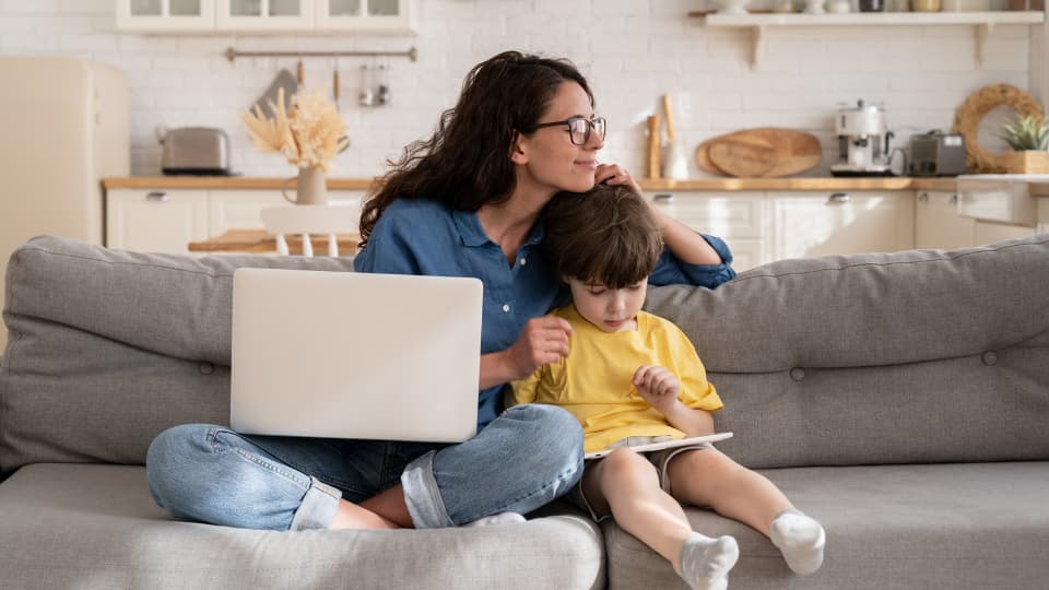 femme qui prend soin de son enfant sur un canapé en travaillant